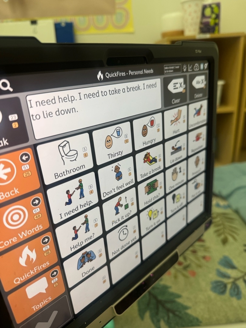 A Tobii Dynavox AAC device showing a Personal Needs board with symbols for Bathroom, Thirsty, Hungry, Take a break, and other everyday phrases.